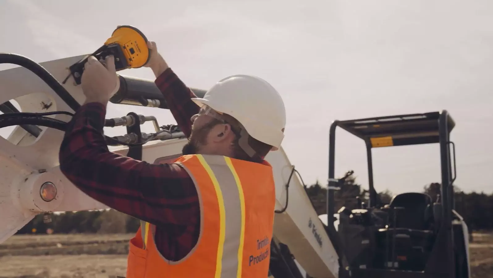 Man attaching antenna onto excavator 